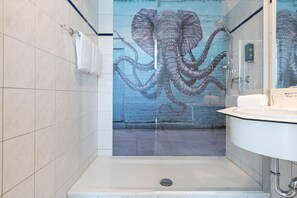 A modern bathroom with a glass shower enclosure, a white sink, and a large octopus mural on the wall. - Seminaris Sunday Hotel Potsdam Babelsberg (Potsdam)