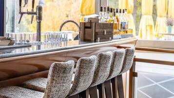 Zona de bar con mostrador, taburetes y una variedad de botellas.