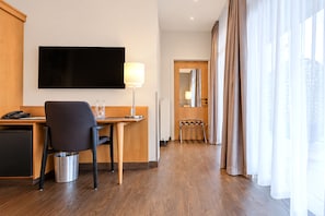 A hotel room with a desk, chair, television, lamp, and a view of the hallway. - Seminaris Sunday Hotel Potsdam Babelsberg (Potsdam)