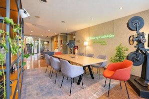 A modern conference room with a long table, several chairs, a neon quote on the wall, and a vintage projector. - Seminaris Sunday Hotel Potsdam Babelsberg (Potsdam)
