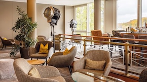 Un espace de détente moderne, doté de sièges confortables, d’une table basse en verre et d’une grande fenêtre donnant sur l’extérieur.