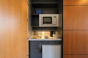 A compact kitchenette with a microwave, sink, and a small refrigerator. - Seminaris Sunday Hotel Potsdam Babelsberg (Potsdam)