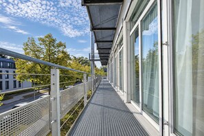 A modern building with a covered outdoor walkway, large windows, and a metal railing. - Seminaris Sunday Hotel Potsdam Babelsberg (Potsdam)