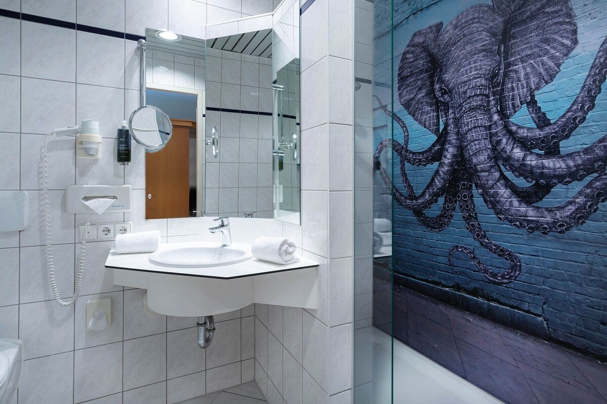 A modern bathroom with a white sink, mirror, and a glass shower enclosure.