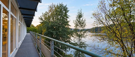 A balcony with a metal railing overlooking a body of water and trees.