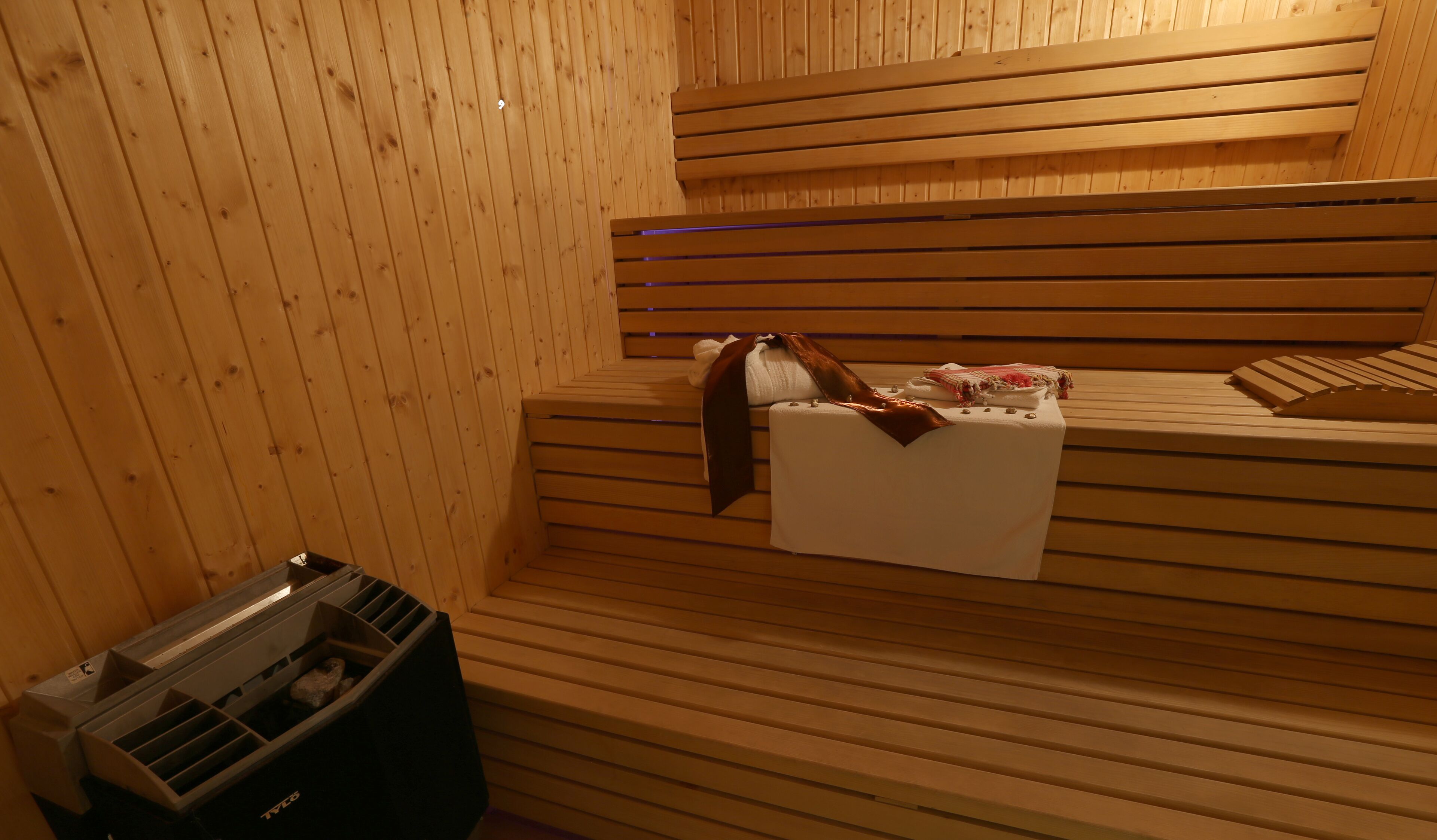 Un sauna avec des bancs en bois, une serviette et un revêtement pour les bancs.