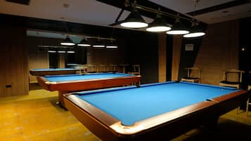 Ein Billardtisch mit blauer Spielbahn, umgeben von Holzwänden und einem gelben Boden.