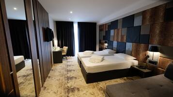 A hotel room with two beds, a desk, a chair, and a sofa.