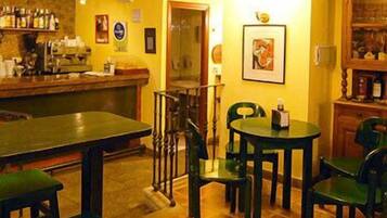 A bar area with a counter, stools, and a table with chairs. There is a staircase leading to another room.