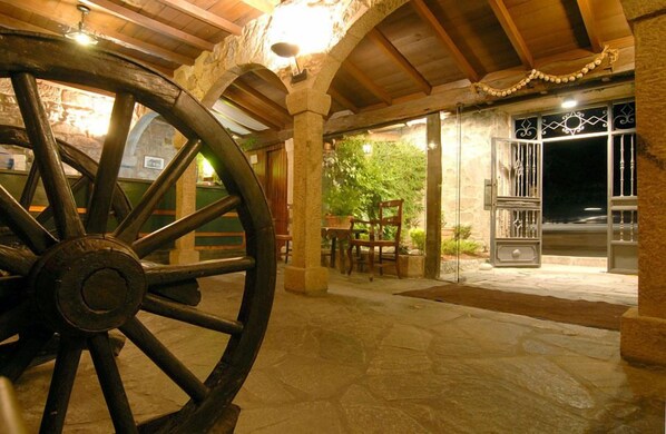 Un patio al aire libre con suelo de piedra, mobiliario de madera y una gran estructura circular de madera.