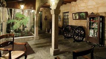 Un interior rústico con paredes de piedra, muebles de madera y un amplio ventanal con vistas a la vegetación.