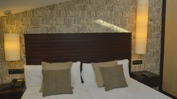 A hotel room with a large bed, two bedside lamps, a nightstand with a phone, and a wall with a repeating pattern.