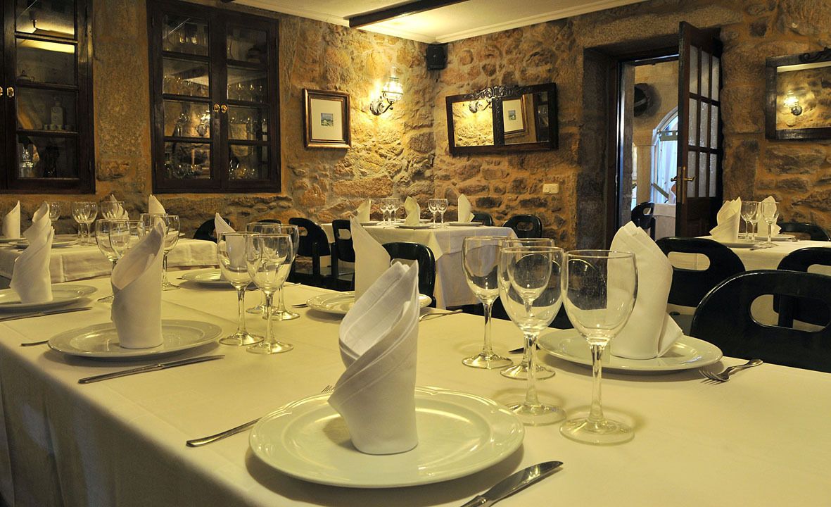 Un restaurante con mesas dispuestas para comer, con manteles blancos, platos y copas de vino.