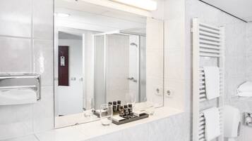 Un baño moderno con un espejo grande, un perchero para toallas y una cabina de ducha de cristal.