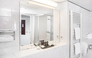 A modern bathroom with a large mirror, a towel rack, and a glass shower enclosure. - Greenside (De Koog)