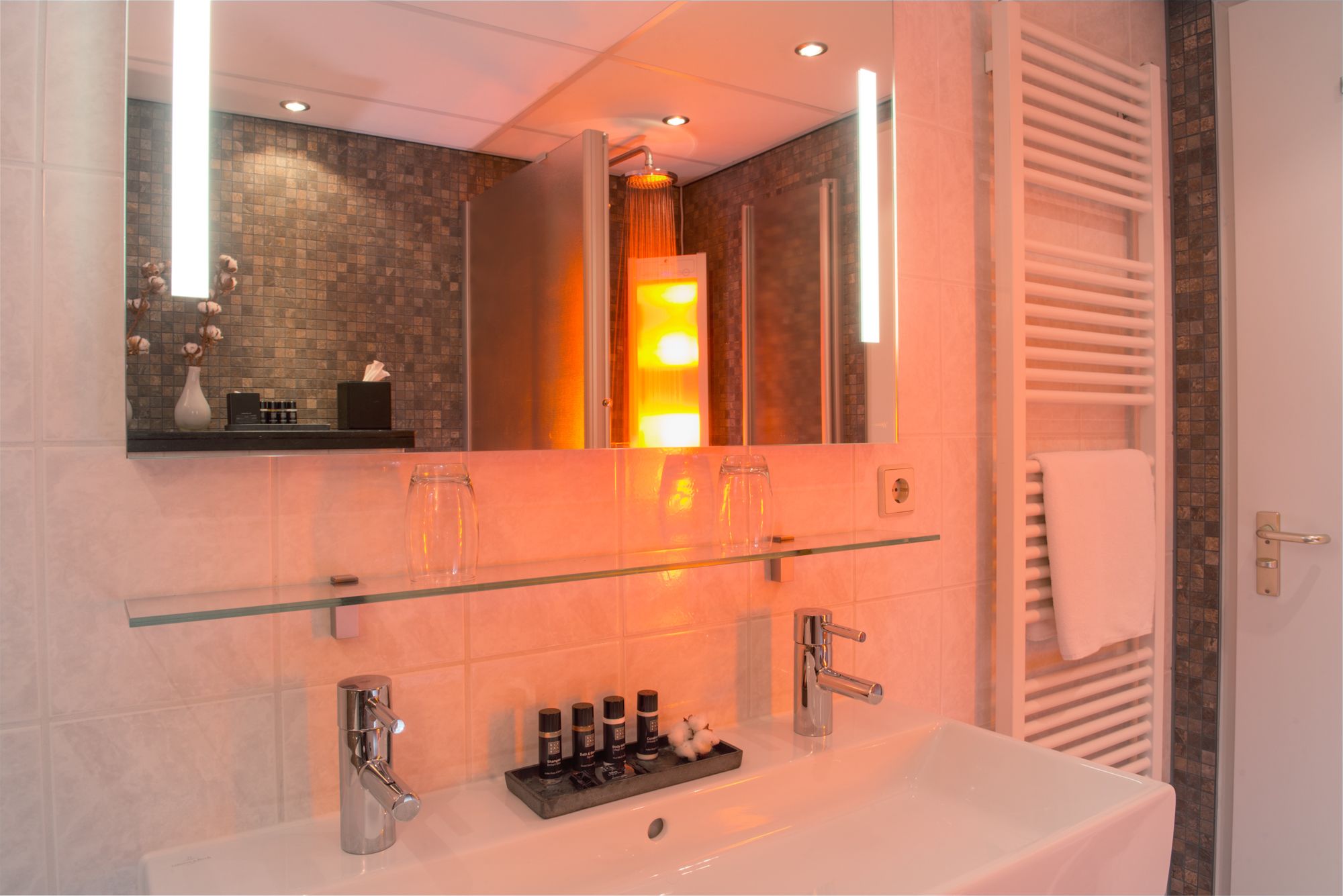 A modern bathroom with a glass shelf, a white sink, and a large mirror.