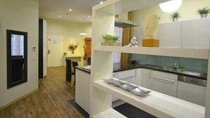 A modern kitchen with white cabinetry, a black countertop, and a built-in oven. - Pension A Und A (Vienna)