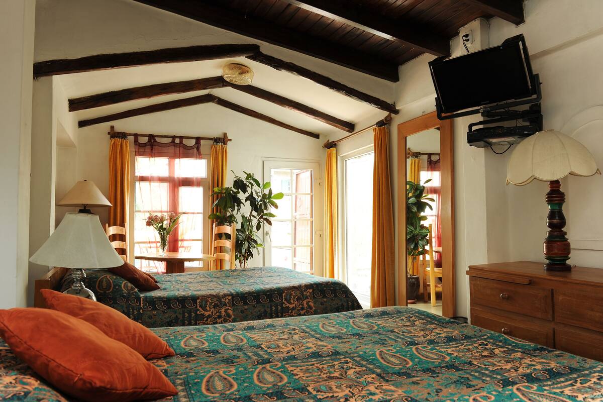 A room with two beds, a television, a lamp, and a dresser.