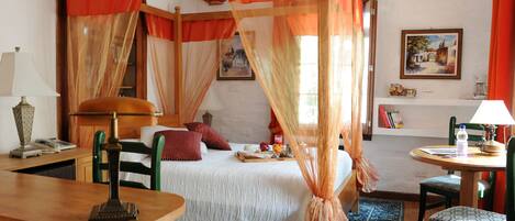 Cozy retreat with a four-poster bed, wooden desk, and comfortable seating area.
