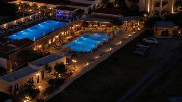 Un resort con dos piscinas, zonas de estar al aire libre y un bar.