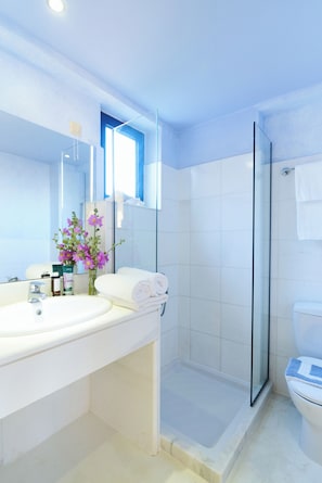 Un baño con cabina de ducha de vidrio, lavabo blanco y espejo.