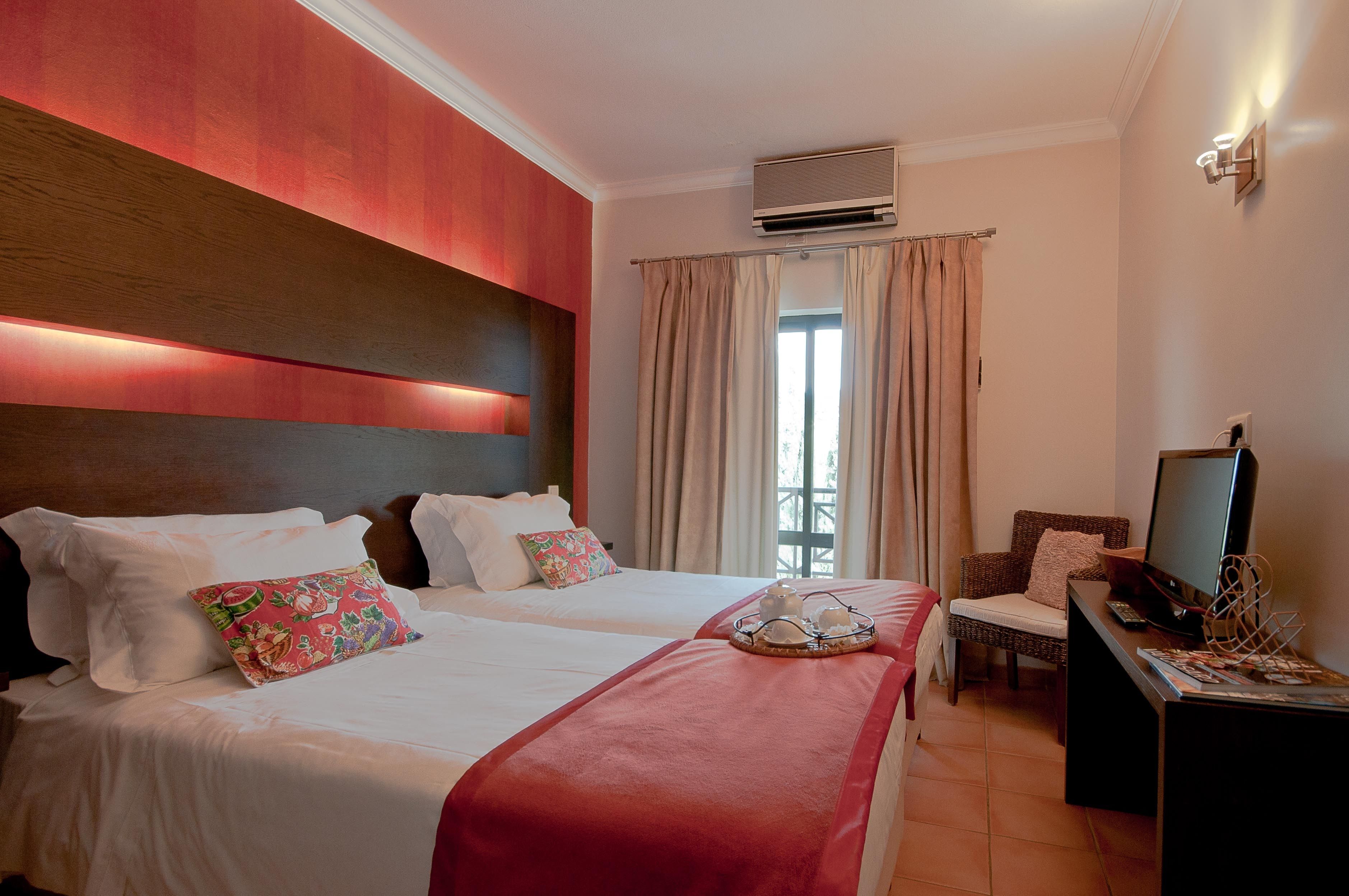 Habitación de hotel con dos camas, un escritorio con computadora y una ventana con cortinas.