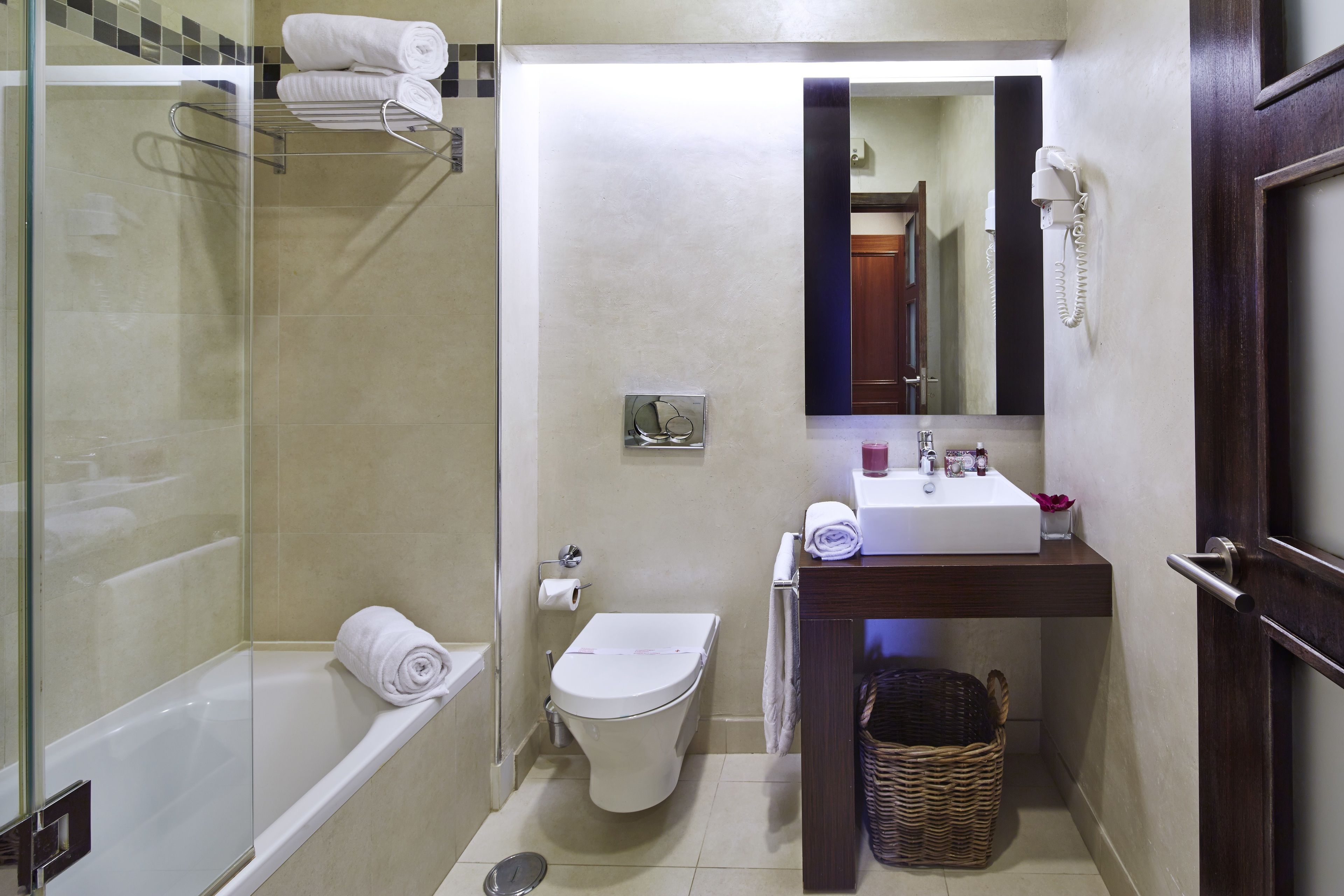 A compact bathroom with a glass-enclosed shower, a toilet, a sink, and a mirror.