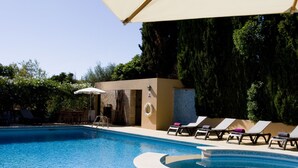 A poolside breakfast setup with a tray of croissants, coffee, and orange juice, a lounge chair, and a sun umbrella. - Parque Das Laranjeiras (Loulé)
