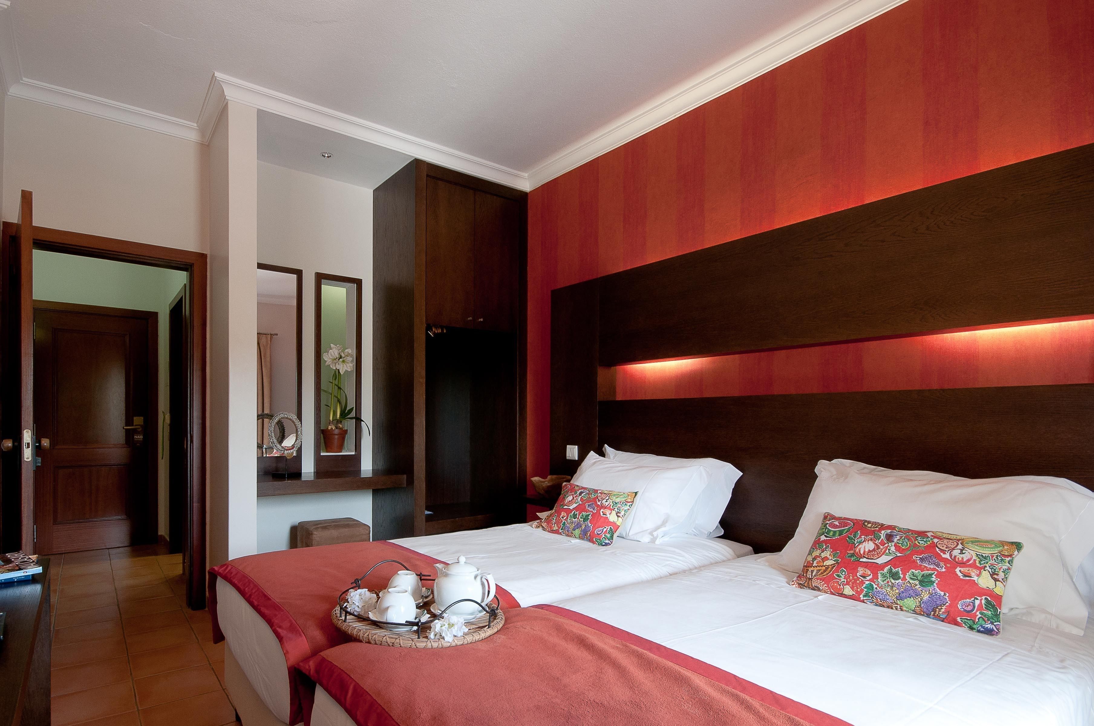 Habitación de hotel con una cama grande, cabecero de madera y una bandeja de desayuno sobre la cama.