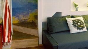 Et værelse med et vægmaleri af et bybillede, en sofa med en pude, og et skilt med teksten 'Walk INN Váci'.