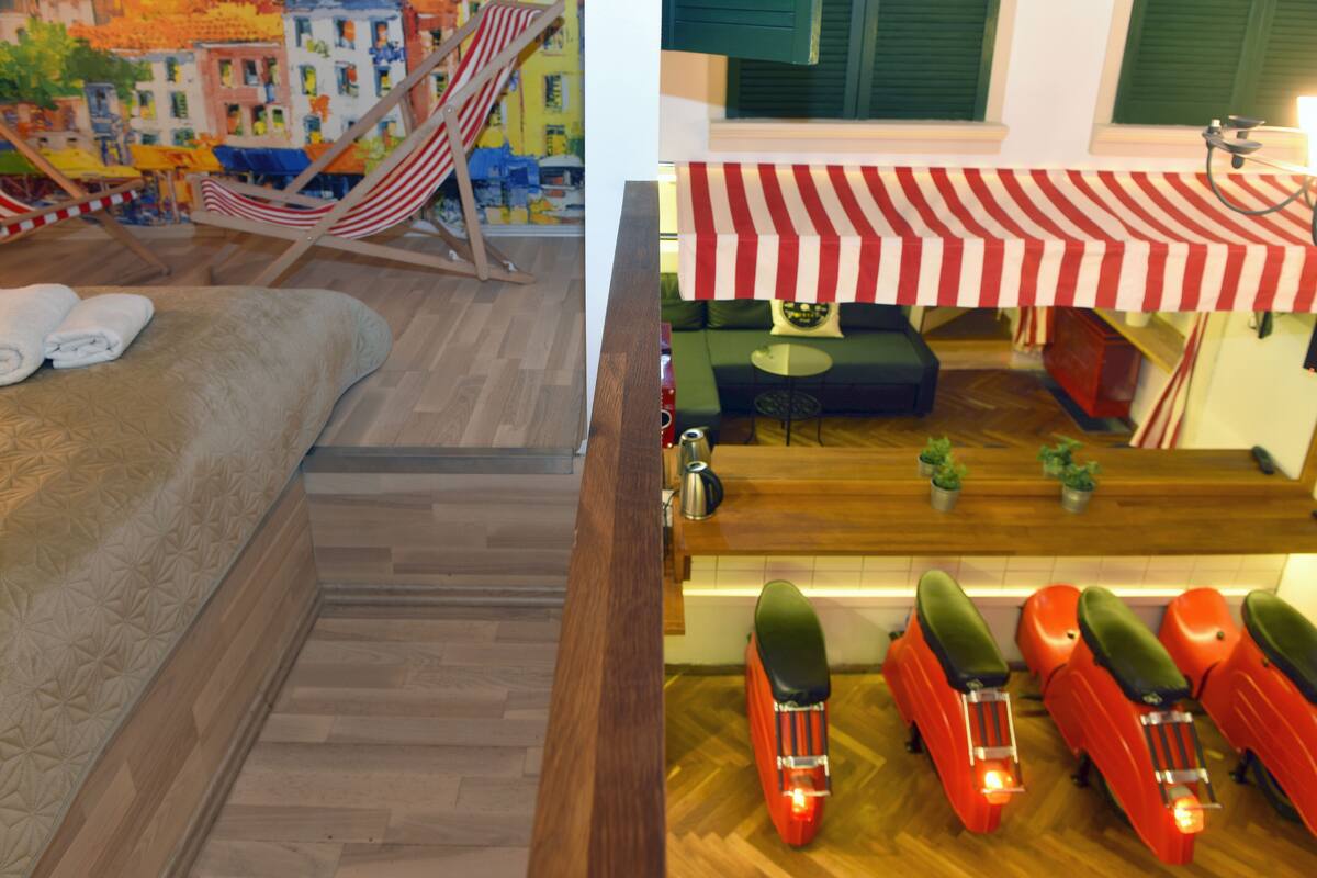 A room with a bed, a hammock, a small table, and a red scooter.