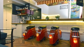 Et moderne køkken med mikroovn, hylder og en potteplante. Tre røde scootere står på række langs væggen.