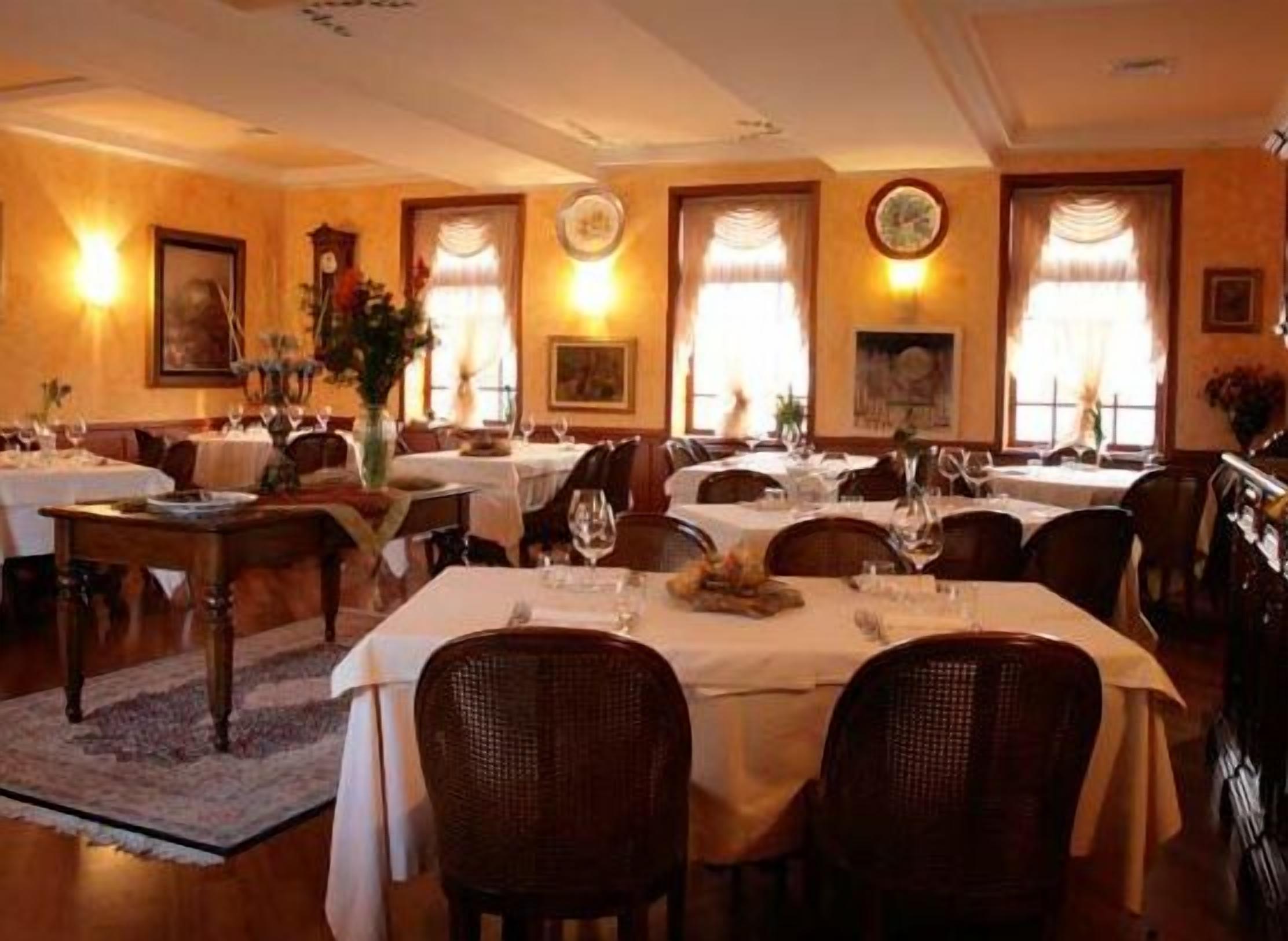 Un restaurante con varias mesas dispuestas para comer, que presenta un interior clásico con mobiliario de madera e iluminación cálida.