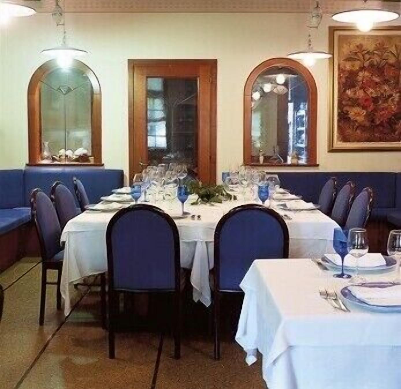 A restaurant with a long dining table set for a meal, surrounded by blue upholstered booths.