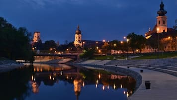 Nachtansicht eines historischen Gebäudes mit einem markanten Turm und Spiegelung in ruhigem Wasser.