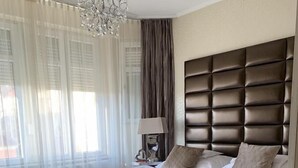 A bedroom with a large bed, a chandelier, and a nightstand with a lamp. - Hunyadi (Gyor)
