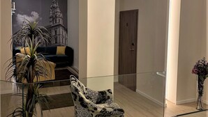 A modern living room with a glass coffee table, a patterned armchair, a potted plant, and a chandelier. - Hunyadi (Gyor)
