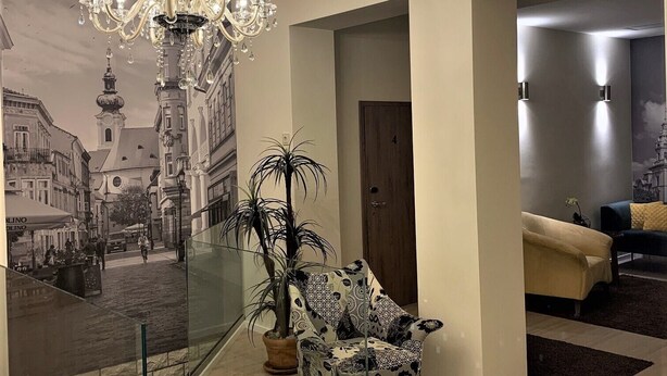 A modern living room with a chandelier, a patterned armchair, and a large mural of a city street. - Hunyadi (Gyor)