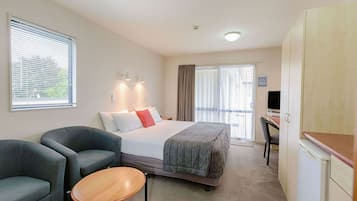 Habitación de hotel con cama, dos sillones, una mesita, un escritorio y televisor.
