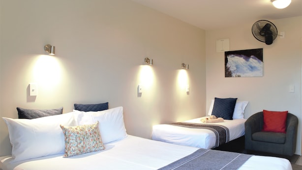 A hotel room with two beds, a chair, and a ceiling fan. - Bella Vista Taupo (Taupo)