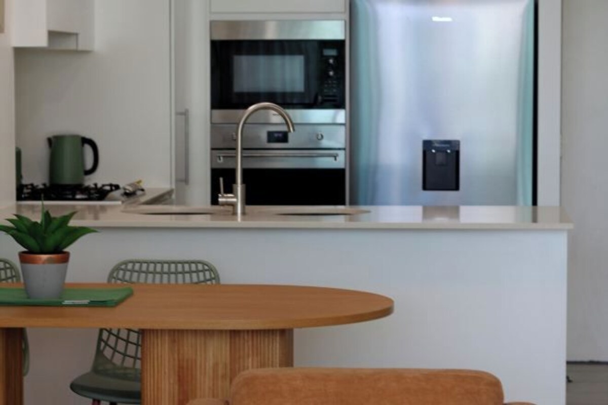 A modern kitchen with a stainless steel refrigerator, a built-in oven, and a microwave.