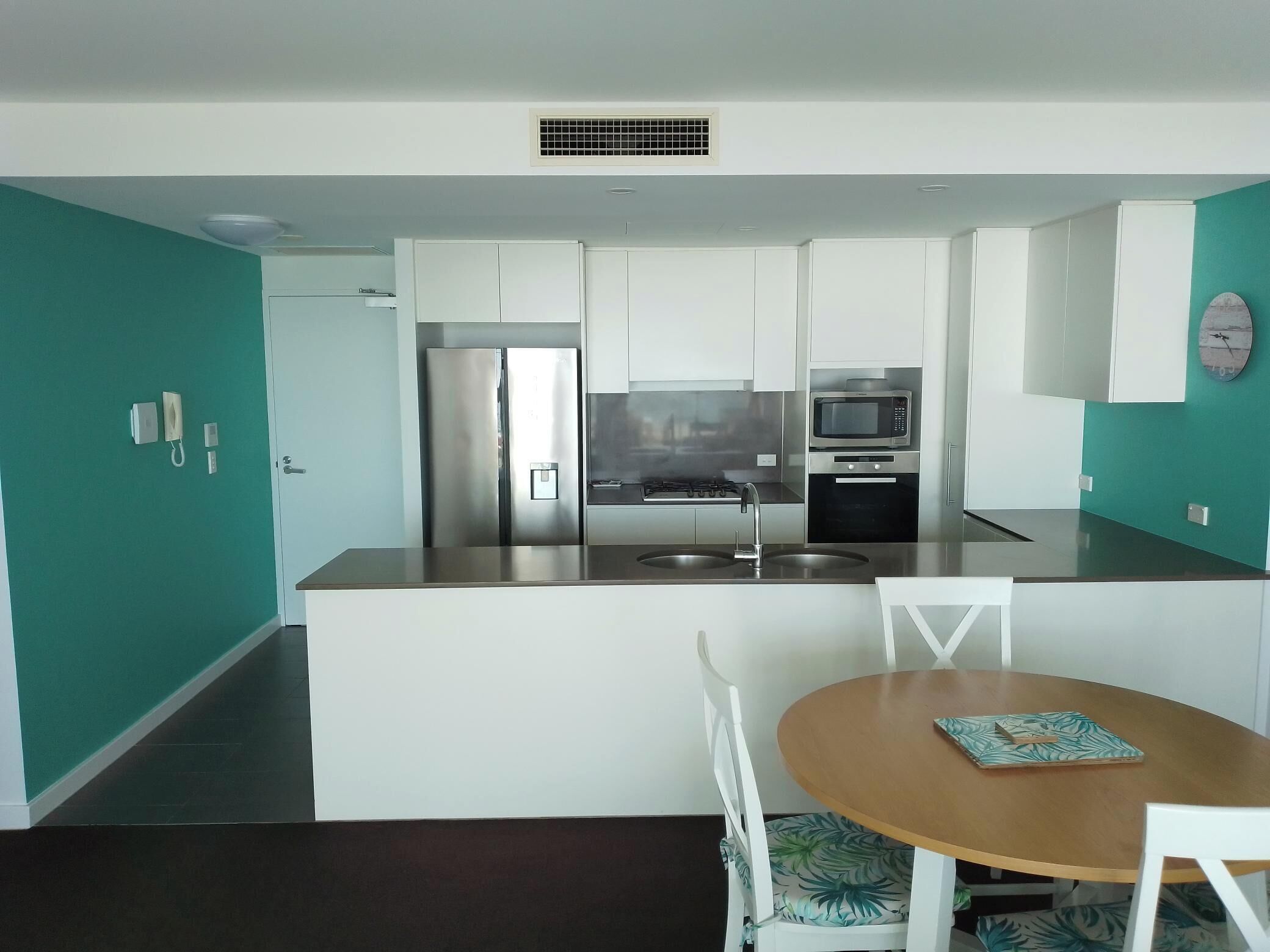 A modern kitchen with white cabinets, stainless steel appliances, and a central island with a sink.