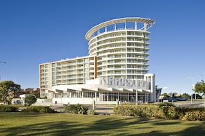A modern hotel with a curved facade, multiple balconies, and a prominent entrance.