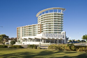Un hotel moderno con fachada curva, varios balcones y una entrada destacada.