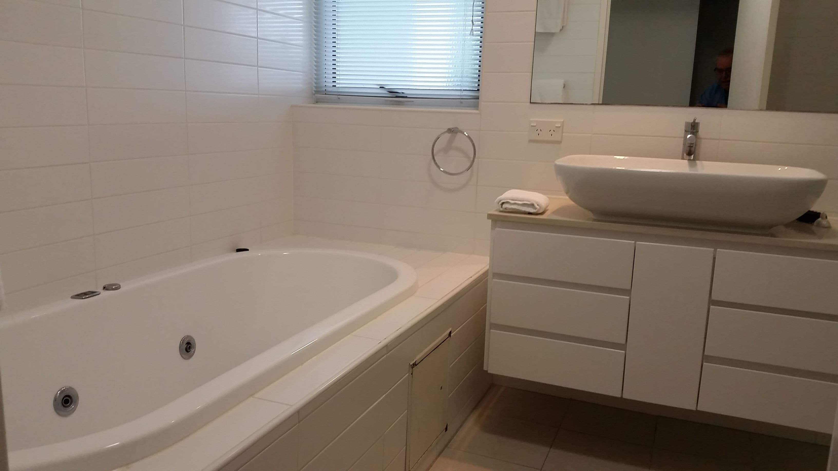 A bathroom with a white bathtub, a sink, and a mirror.