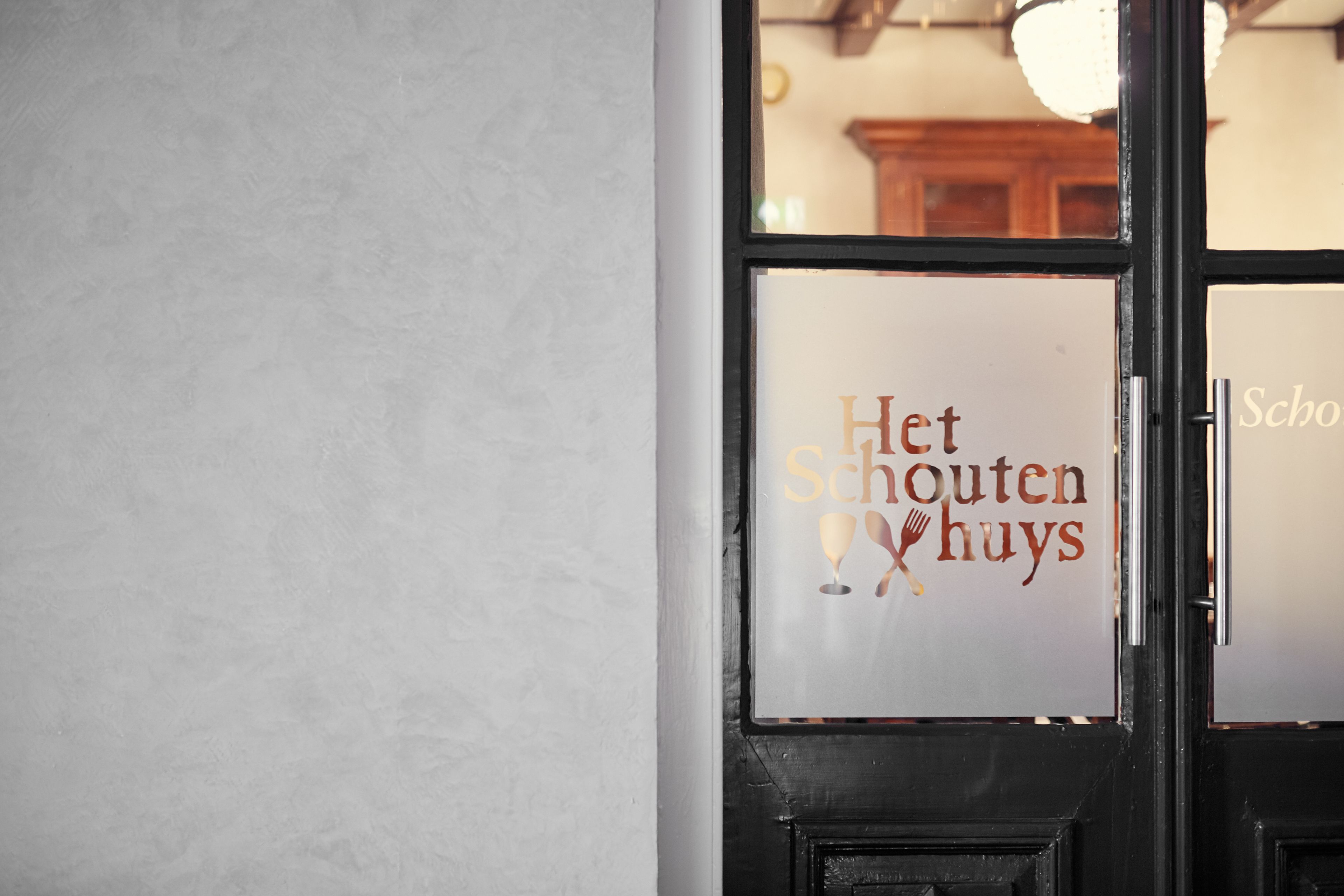 A door with a sign that reads "Het Schouten huys".