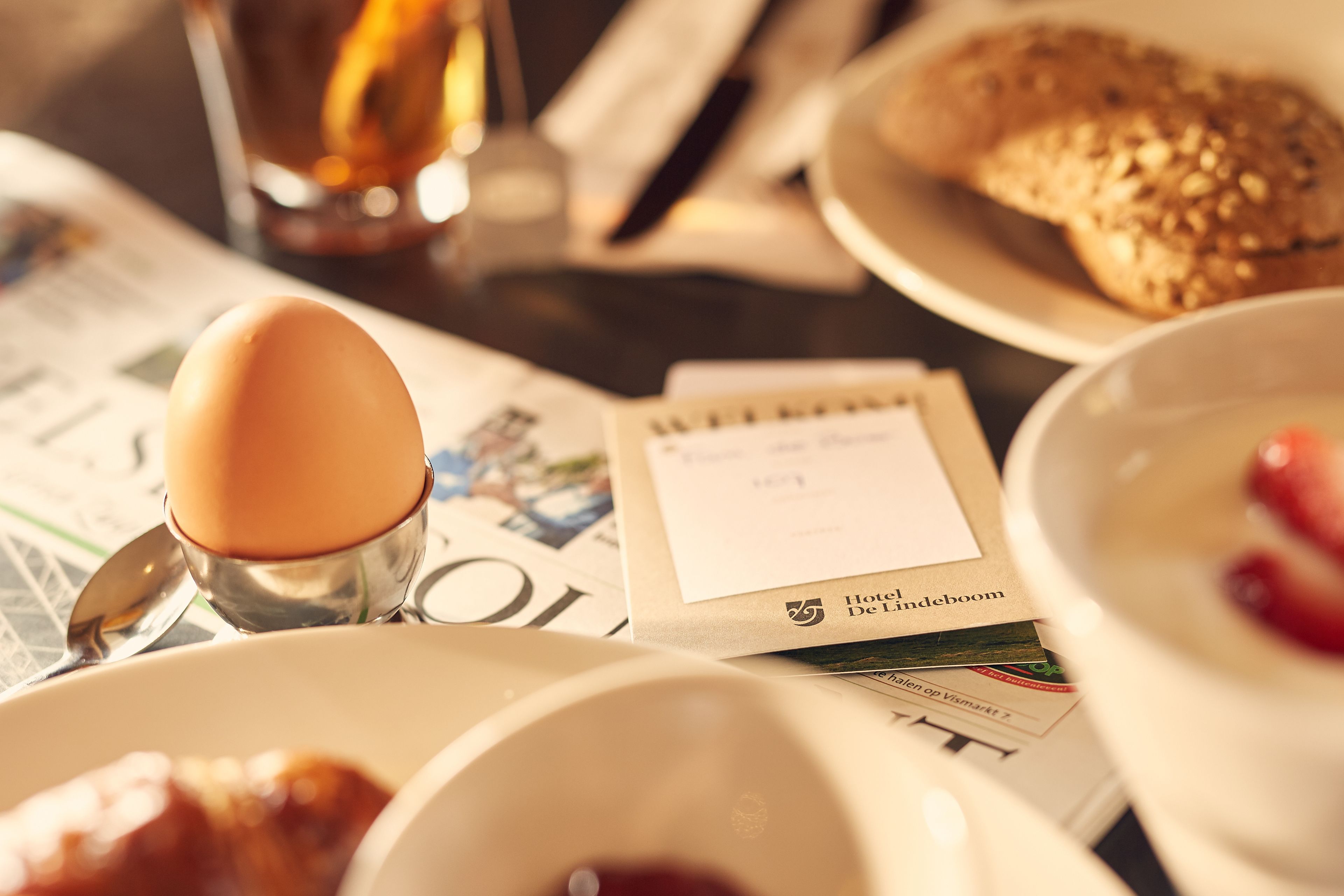Ein Frühstückstisch mit Zeitung, Kaffeetasse, Brot und einer Schüssel Suppe.