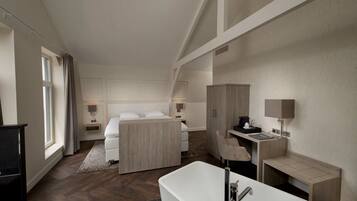 A modern hotel room with a large bed, a desk, a chair, a bathtub, and a wardrobe.