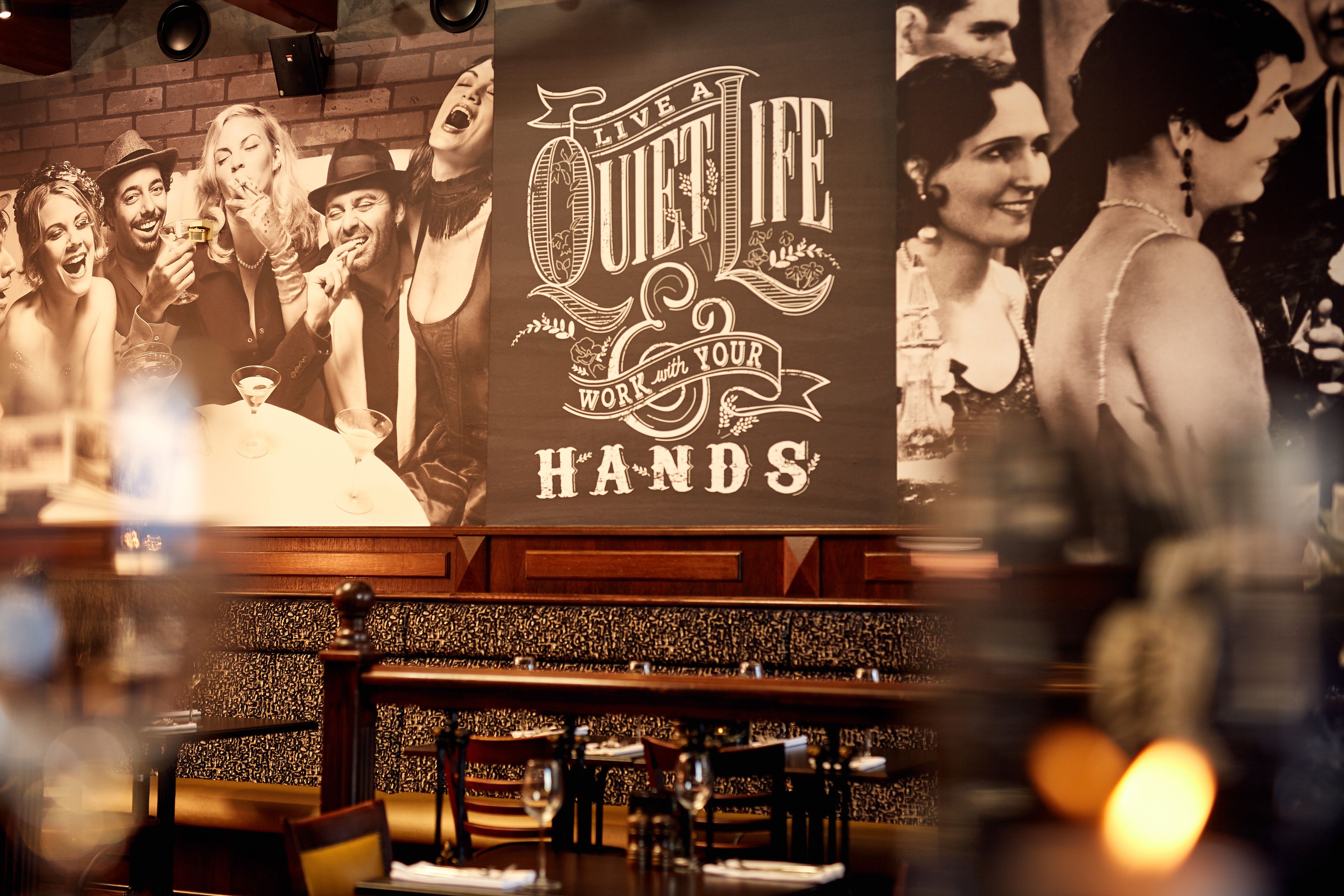 L’intérieur d’un restaurant, avec une grande affiche accrochée au mur, des tables, des chaises et un mur en briques.