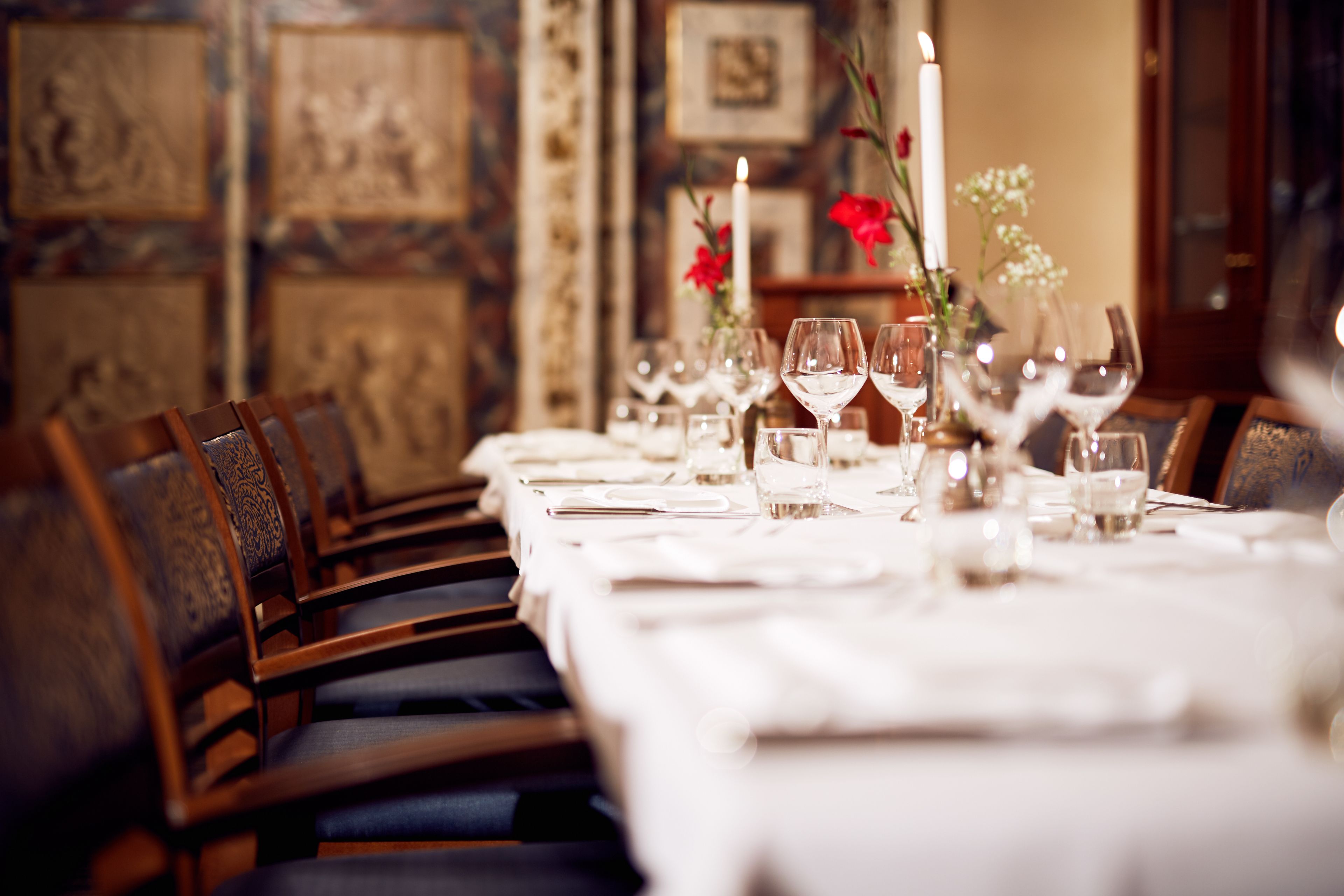 A dining table set with chairs, candles, and floral arrangements.